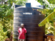 Felicio Fundi is a young, dedicated farmer residing in Rianjeru village, Mbeti South, Embu County. He is a loving husband and also a proud father of one. Felicio bears the essential responsibility of providing for his family, and he achieves this through a diverse array of agricultural pursuits, including dairy farming, pawpaw cultivation, and banana farming. In the semi-arid region of Rianjeru, clean water is scarce. The community depends on the "Rupingazi Rweru" water project, funded by the World Bank, but water is only available on specific days. During dry seasons, residents often go an entire week without any water. Felicio and his young family faced significant challenges, struggling to secure enough water for their crops, livestock, and daily needs. They often stayed up all night collecting and storing water when it's accessible, leaving them vulnerable to bandits and troublemakers who exploit the darkness. This situation made life difficult and dangerous for them. This predicament weighed heavily on Felicio, as it began to slow down his ability to manage the day-to-day activities on his farm. At times, he resorted to hiring a water tanker, which came at a steep cost of Ksh 3,000 for 6,000 liters of water, necessitating five deliveries in a month. This was not only financially burdensome but also unsustainable in the long run. Felicio yearned for a lasting and secure water solution for his family. Fortunately, Felicio was a member of BIMAS Microfinance, where he had been tapping into loans to support his farming endeavors. In March 2021, he received news that BIMAS was offering financing for water tanks to its customers. This was a golden opportunity for him to finally experience an abundance of water in his home. With the support of BIMAS, Felicio secured a loan of Ksh 78,000, enabling him to purchase and install a substantial 10,000-liter water tank on his property. The transformation was worth it. The family was no longer at the mercy of dry seasons; they now had a reliable and ample water supply for both their domestic needs and farming activities. Felicio's family life took a turn for the better. He radiated happiness as a father and husband. With their newfound water security, the family harbors ambitious plans to expand their farming enterprise. They even own another farm situated near a river, and BIMAS's support extends to financing the purchase of a water pump for this venture. In Felicio's own words, he joyfully exclaims, "I can now farm with confidence throughout the year. My small-scale farming business has thrived since partnering with BIMAS. We are no longer constrained, and our lives are no longer endangered during the night. We can rest early and wake up refreshed to tend to our farming." Felicio’s success story highlights BIMAS Microfinance's commitment to Sustainable Development Goal 6 by ensuring sustainable water management. By financing water tanks and pumps, BIMAS tackles water scarcity in semi-arid regions like Rianjeru, enhancing farmers' quality of life and promoting sustainable agriculture. This support boosts both economic and social well-being in the community, demonstrating a commitment to improving water access and management.
