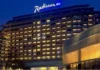 Radisson Hotel Group has reached a significant milestone in Africa, with more than 100 hotels across the continent in operation and under development. Radisson Blu continues to anchor the legacy footprint. At the same time, the Radisson brand is the fastest riser, supported by a strong conversion engine and a concrete pipeline that continues to translate into openings. Building on this momentum, the Group has signed over 15 new hotels and roughly 2,500 rooms in the last 12 months, including new market entries in the Democratic Republic of Congo and Zimbabwe. This week, Radisson Hotel Group is also attending FHS Africa (www.FutureHospitality.com) in Nairobi, reinforcing its commitment to expanding its presence and strengthening strategic partnerships across the continent. Over the past five years, Radisson and Radisson Blu have ranked among the most signed brands in Africa, with one of the highest shares of cumulative openings. The last 12 months set a new benchmark with more than 2,500 rooms signed and multiple market entries. Priority growth markets remain Morocco, South Africa, and Nigeria, where the Group is deepening its presence and widening its brand distribution. Ramsay Rankoussi, Regional Chief Development Officer, Radisson Hotel Group, commented: “We’ve crossed the 100-hotel mark in Africa by staying true to our plan, focusing on where we can lead, moving fast on quality conversions, and partnering with owners who share our ambition. The next phase is about depth in Morocco and Nigeria, a smarter footprint in South Africa, and a stronger resort offering that matches where travelers want to go. Our pipeline is built to open, not just to announce. That is why our conversion share is high, our time to market is short, and our brands are gaining ground in the cities and resort destinations that matter most.” Nigeria shows the model’s resilience. The Group now holds a strong position in the country with 13 hotels in operation and pipeline, while Abuja is carrying a significant active pipeline with three hotels totaling 458 keys. South Africa is being reshaped with priorities in Cape Town, targeted growth in secondary cities such as Durban and Pretoria, and a sharper focus on leisure corridors that include Kruger National Park, Sun City, and the Garden Route. The Group plans to enter Zanzibar and is considering lodge, safari, and affiliation opportunities across Namibia, Botswana, and Zambia to meet the rising demand for nature-led experiences. Conversions remain a core lever for scale and speed. In the last five years, more than 15 hotels, equal to almost 3,000 rooms, joined the portfolio through conversion. This helped the Group lead openings across the continent while keeping brand standards high and owners in mind. Recent signings show the extensiveness of this strategy, with a balanced pipeline of city hotels, resort destinations, and quick-to-market conversions. These signings span the Democratic Republic of Congo, Nigeria, Zimbabwe, and Morocco, including Radisson Blu Kinshasa and three Radisson hotels in Lubumbashi, Radisson Harare, Park Inn Victoria Falls, Radisson Collection Lagos Atlantic, as well as new additions in Casablanca with Radisson Blu Resort & Conference Center Bouskoura, a first Radisson brand hotel in Rabat, and further expansion in Marrakech. Key signings include: Democratic Republic of the Congo Radisson Blu Hotel, Kinshasa Upper-upscale flagship in Gombe Opening late 2026. Set on Boulevard Colonel Tshatshi in the Gombe district, the hotel will offer 110 keys, including suites and a Presidential Suite. Guests can choose from a lobby bar, an all-day dining restaurant, and a pool bar. Wellness includes a gym, massage rooms, and an outdoor pool with a terrace. Meetings and events feature a modern event hall with a pre-function area. The address is well connected, 32 kilometers from N’djili International Airport, 10 kilometers from N’Dolo Airport, and 6 kilometers from Gare Centrale. Radisson Hotel Lubumbashi Panoramic city stay in the DRC’s second city Opening mid-2027. Located on Revolution Road Avenue, the hotel will feature 97 keys, including junior suites and a Presidential Suite. Dining spans a lobby bar, an all-day dining venue, and a rooftop bar and grill with city views. Three flexible meeting rooms and a pre-function area support business and social events. Facilities include a gym and a swimming pool. The location sits near Kipopo Lake, Lubumbashi Golf Club, and La Plage, and is 12 kilometers from Luano International Airport. Radisson Blu Apartments Lubumbashi Upscale apartment living in Lubumbashi’s prestigious Quartier Golf Targeted for 2030. A 160-room property located in Quartier Golf, one of Lubumbashi’s most upscale residential districts, near Kipopo Lake and surrounded by luxury homes and key landmarks including Lubumbashi Golf and La Plage. Planned amenities include a specialty restaurant and bar, a pool bar, and a gym, offering a premium stay experience for extended-stay and leisure travelers. Radisson Airport Hotel Lubumbashi A strategically located airport hotel designed for ease and connectivity Set to open in 2028, this 105-room property will be located just 6 kilometers from Luano International Airport, around a 10-minute drive, making it well positioned for business travelers, transit guests, and airline crews. Planned facilities include a restaurant, lobby bar, pool bar, meeting rooms, and a swimming pool, combining practicality with a welcoming hospitality experience close to the airport. Egypt Radisson Resort Ain Sokhna Groove A large-scale Red Sea resort in one of Egypt’s growing leisure destinations Planned for 2029, Radisson Resort Ain Sokhna Groove will offer 469 rooms, including 50 family rooms, as part of The Groove Ain Sokhna mixed-use development. Located along the Red Sea coast, around 30 kilometers south of Ain Sokhna and approximately 150 kilometers from Cairo, the resort is expected to feature private beach access, a spa, gym and fitness center, several restaurants, plus a ballroom and meeting rooms, catering to both holidaymakers and events demand. Radisson Serviced Apartments COY Sheikh Zayed City Flexible extended-stay accommodation in a fast-growing hub of Greater Cairo Expected to open in 2030, this 120-key serviced apartments property, including six one-bedroom units, will form part of the COY development in Sheikh Zayed City. With a location just 13 kilometers from Sphinx International Airport and 14 kilometers from the Great Pyramids of Giza, the development sits close to major commercial, leisure, education, and healthcare destinations. Planned amenities include a coffee lounge, bar, kiosk, and meeting and event space integrated into the wider co-working environment. Morocco Radisson Blu Hotel & Conference Center, Casablanc a Bouskoura Conference-ready address beside Palm Golf A 119-key hotel with eight suites, a rooftop restaurant, and a dedicated conference center. Event facilities include two boardrooms, while a spa and a large outdoor pool cater to leisure travelers. The hotel is located 20 kilometers from Mohammed V International Airport and next to Palm Golf Palmeraie Country Club. Radisson Hotel & Apartments Rabat Technopolis Dual-component hub in the capital’s innovation park A two-building project in Technopolis, 25 minutes from central Rabat. The hotel will offer 140 rooms, four dining venues, a pool, and a meeting and events space. The adjacent serviced apartment building adds 56 units. Technopolis connects businesses with leading education and research centers, creating a strong base for corporate demand. Radisson Blu Resort Marrakech Ben Akil Low-rise bungalows with views of Atlas Mountains Opening early 2028. A 17-hectare estate featuring 80 bungalow-style accommodations, each with an outdoor terrace. Larger typologies include private pools. The resort sits beside Royal Golf Marrakech and is a 15-minute drive from the city center. Nigeria Radisson Hotel Aba A new internationally branded hospitality destination for Aba Targeted for 2031, Radisson Hotel Aba will introduce 120 rooms, including six junior suites, in a prime riverside location along the Aba River near key transport corridors. The hotel will become the first Radisson-branded property in Aba and the Group’s third branded hotel in Nigeria. Plans for the hotel include a gym, swimming pool, and several meeting rooms, serving both business and local demand. Sam Mbakwe International Airport in Owerri is approximately 56 kilometers away, or a 1 hour and 10 minute drive. Radisson Hotel & Conference Center Yenagoa A conference-focused hotel in the heart of an emerging Nigerian business center Scheduled for 2027, the property will feature 196 rooms, including 16 junior suites, four executive suites, and two Presidential Suites, in Yenagoa, a city that is steadily strengthening its role as an administrative and commercial hub in southern Nigeria. Located near government institutions, business districts, and Bayelsa International Airport, approximately 33 kilometers or 40 minutes away, the hotel is set to benefit from the area’s ongoing infrastructure and hospitality growth while meeting rising demand for accommodation, meetings, and large-scale events. Radisson Collection Hotel, Lagos Atlantic Refined lifestyle luxury on the oceanfront of Lagos’ leading business district Targeted for 2029, Radisson Collection Hotel, Lagos Atlantic will feature 107 rooms, including 16 executive suites and one Presidential Suite, on a prime oceanfront site on Victoria Island. As Lagos’ main financial and commercial district, Victoria Island is home to multinational companies, corporate headquarters, embassies, and strong year-round business activity. Located approximately 33 kilometers from Murtala Muhammed International Airport, around a 45-minute drive, the hotel will mark the second Radisson Collection property in Lagos. South Africa Radisson Serviced Apartments Umhlanga A modern serviced apartment offering in the heart of Umhlanga’s business district Planned for 2029, Radisson Serviced Apartments Umhlanga will introduce 155 rooms in a newly built development within Umhlanga Ridge, one of the area’s most established commercial and lifestyle hubs. The property will be within walking distance of Gateway Theatre of Shopping and close to major office precincts, including Umhlanga Ridge Business Park, La Lucia Office Park, and Glass House Office Park. Comprising studios and apartments, the project is designed to meet growing demand for high-quality extended-stay accommodation in the district. Zimbabwe New market entry Radisson Serviced Apartments, Harare Prime Borrowdale address for extended stays Targeted for end-2028. A 147-key serviced apartments project within a master development near Maxwell Road in Borrowdale. The neighborhood is known for luxury residences, upscale shopping at Sam Levy’s Village, and entertainment at Borrowdale Racecourse. Planned amenities include a café and bar, a gym with sauna, and a pool with a deck. Set to be the only internationally branded hotel apartment offering in the area. Park Inn by Radisson Victoria Falls Resort A resort destination near one of the world’s most iconic natural landmarks Expected to open in 2029, Park Inn by Radisson Victoria Falls Resort will offer 150 rooms, including five suites, in a setting overlooking Zambezi National Park. Located just 5 kilometers from Victoria Falls, around a 10-minute drive, the resort will be ideally positioned near one of the Seven Natural Wonders of the World, a destination that attracts more than 350,000 international visitors each year. With year-round waterfall views, adventure tourism, and access to safari experiences in the surrounding national parks, the property will cater to both leisure travelers and tour groups. Victoria Falls Airport is located approximately 22 kilometers, or a 23-minute drive, away. Leading with the most diverse footprint across the continent, with presence in more than 30 African countries, Radisson Hotel Group blends depth in focus markets with selective entry into new destinations each year.
